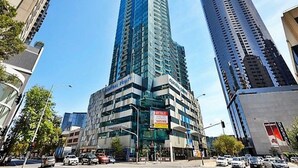 Un edificio alto y moderno con fachada de vidrio, rodeado de otros rascacielos.