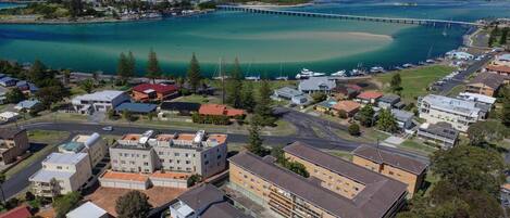 An aerial view of a coastal town with a prominent bridge, clear turquoise waters, and a mix of residential buildings.