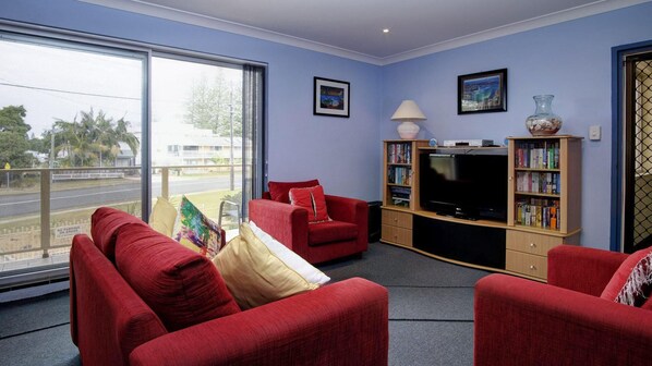 A living room with red sofas, a TV, and a bookshelf.