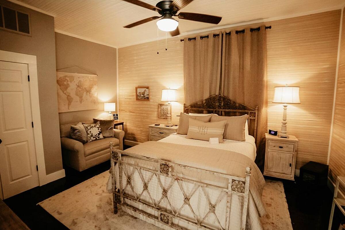 A bedroom with a bed, a nightstand, a lamp, a dresser, and a ceiling fan.