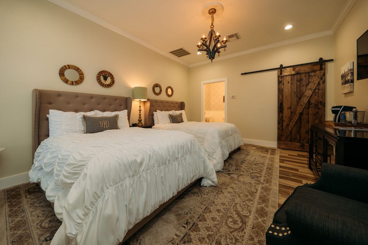 A bedroom with a large bed, a chandelier, and a wooden door.