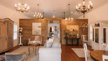 A spacious living room with wooden walls, a white sofa, and a dining table.