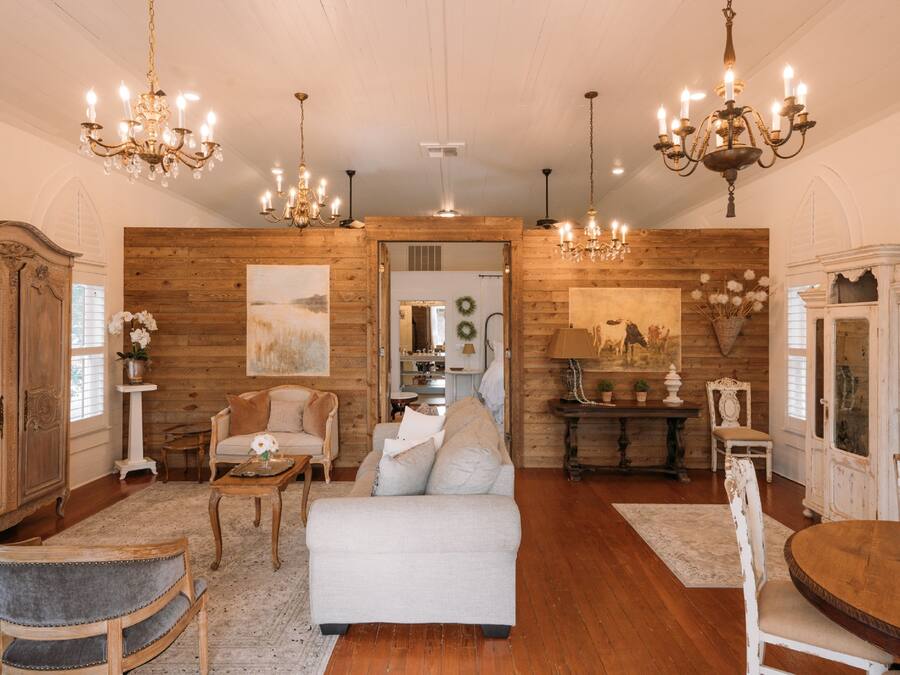 A spacious living room with wooden walls, a white sofa, and a dining table.