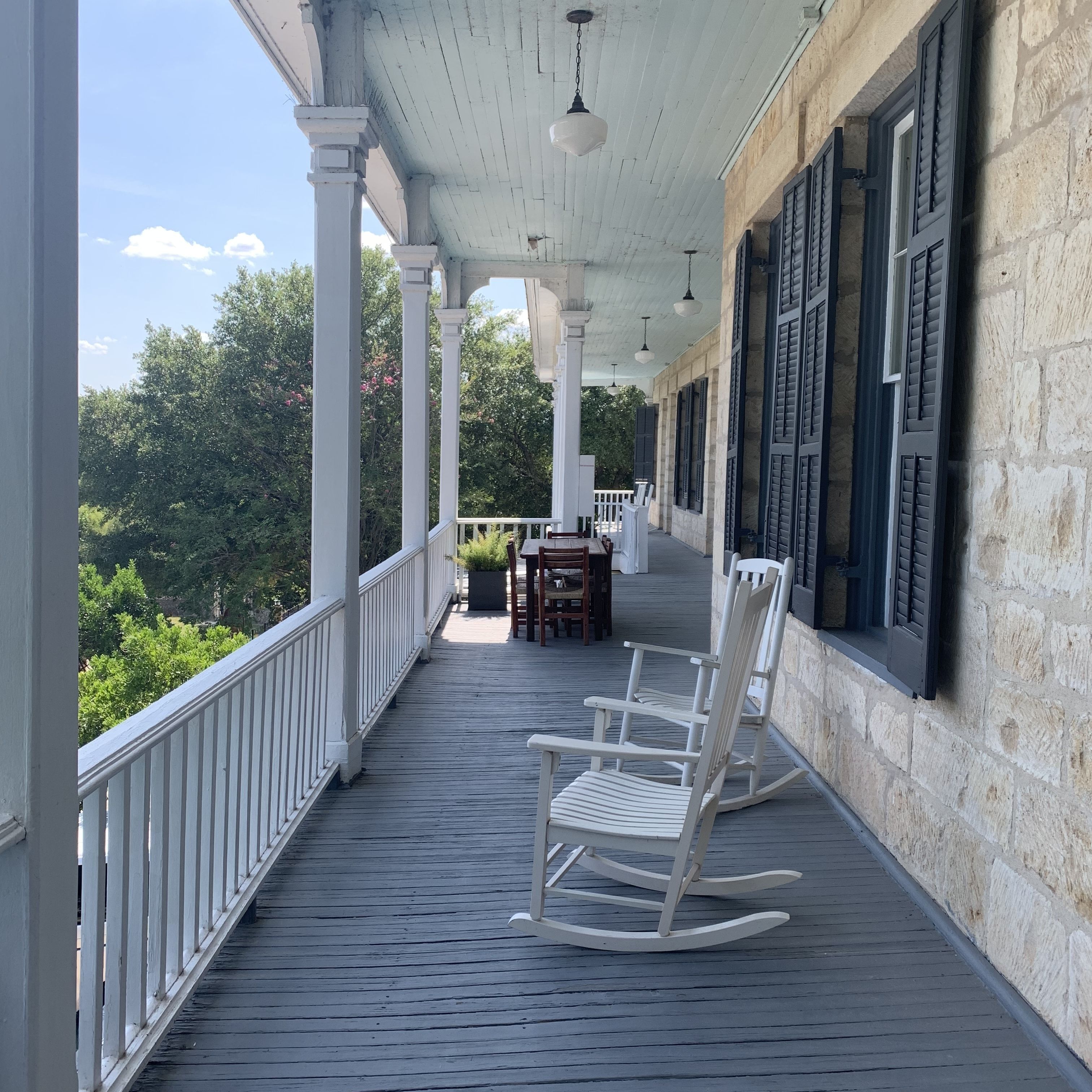 A covered porch with white railings, a wooden floor, and a rocking chair.