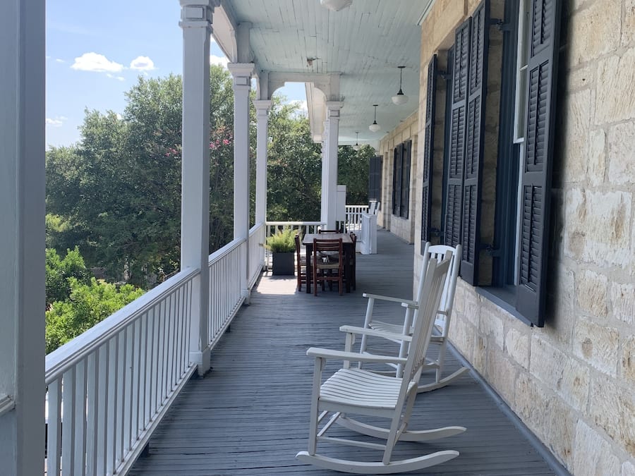 A covered porch with white railings, a wooden floor, and a rocking chair.
