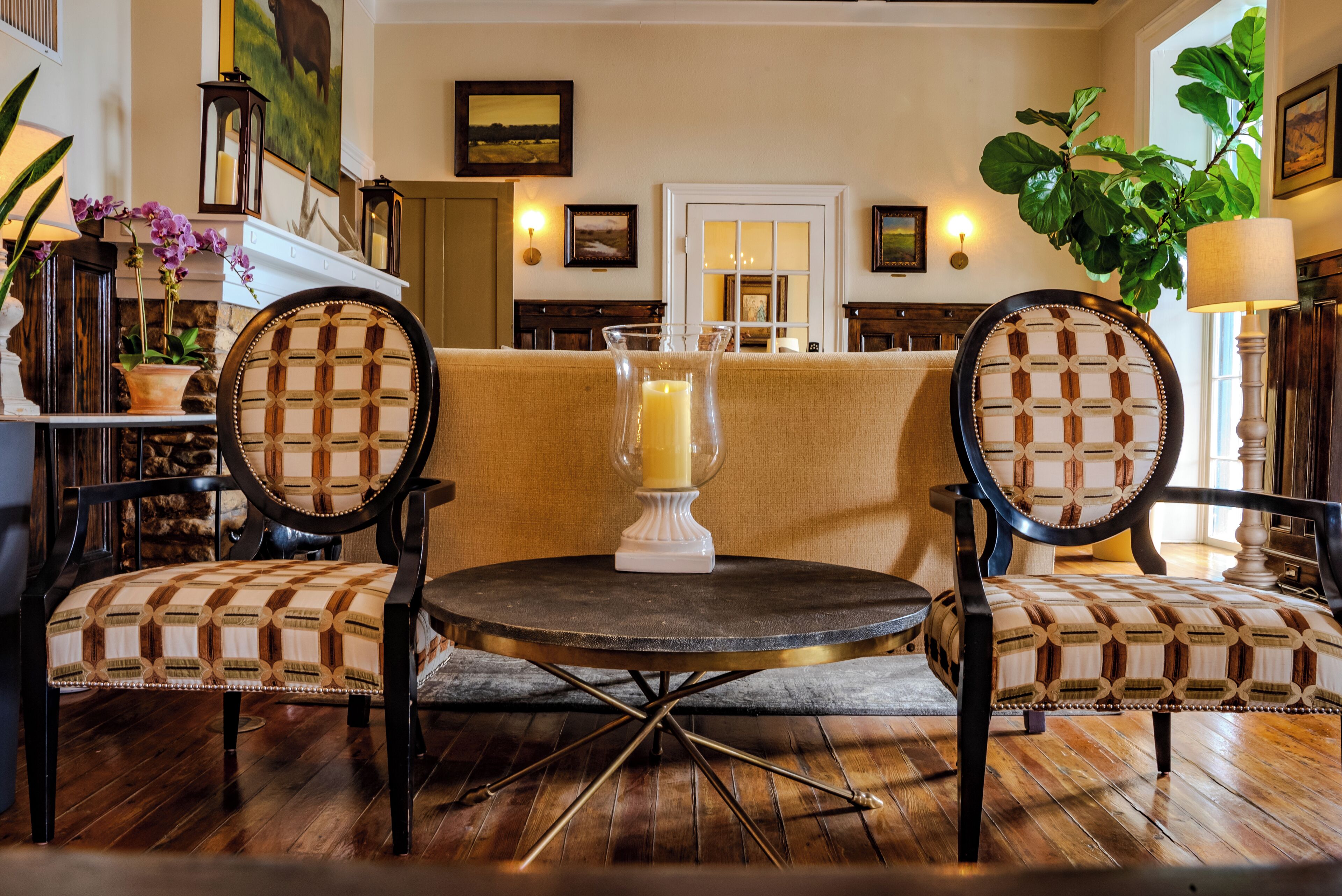 A cozy seating area with two upholstered chairs, a round table, and a vase with a candle.