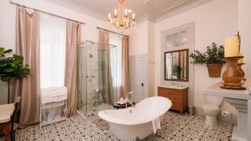 A bathroom with a freestanding bathtub, a glass shower enclosure, a vanity with a mirror, and a potted plant.
