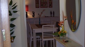 A dining area with a white table and chairs, a mirror, and a vase with flowers. - Exquisite Poolside Apt at the fabulous Oasis Parque. Unlimited WiFi IPTV etc (Portimão)