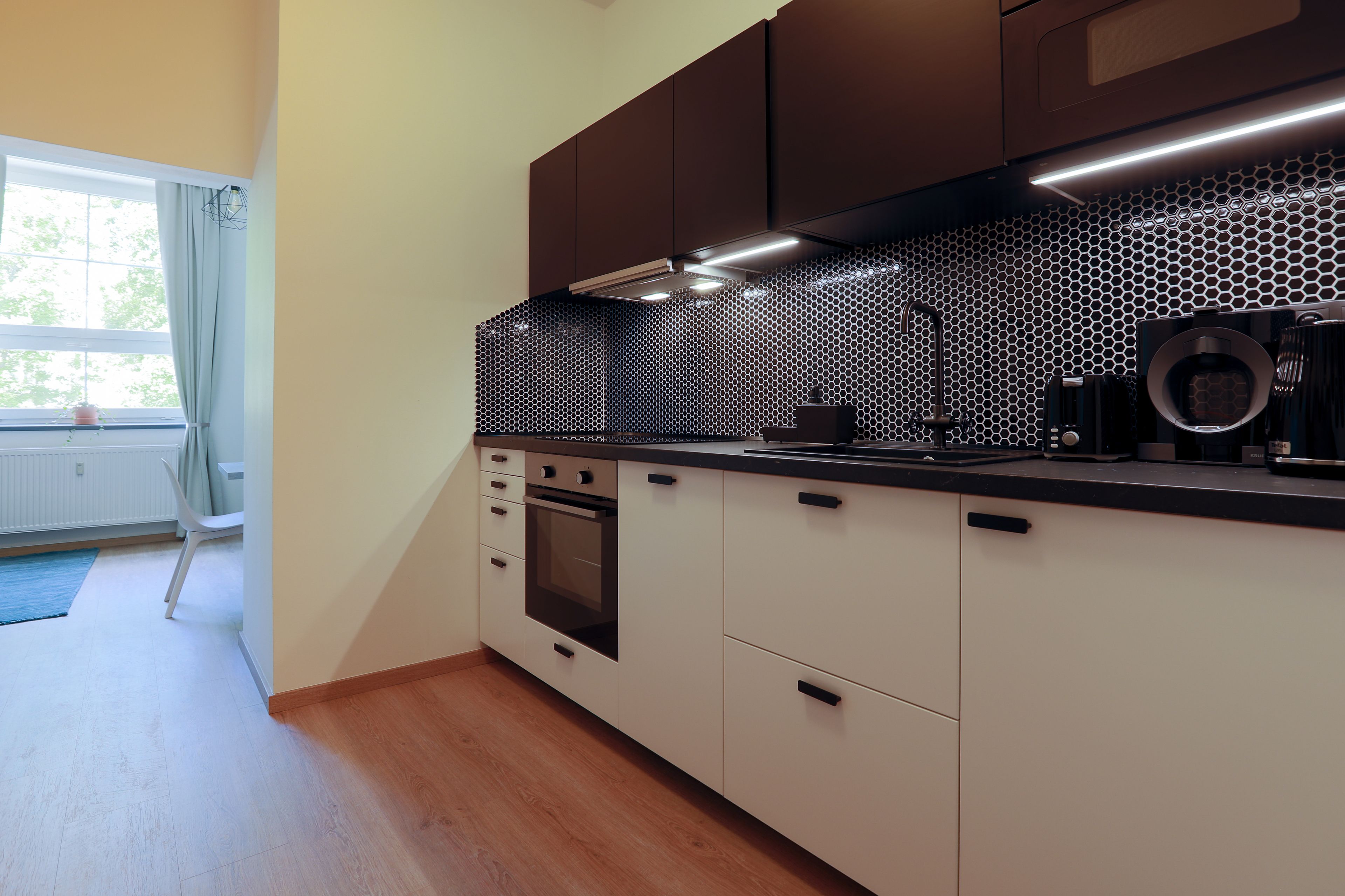 A modern kitchen with a built-in oven, a microwave, and a coffee machine.
