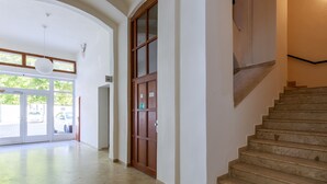 A hotel lobby with a staircase, a large wooden door, and a view of the outside. - Avantgarde apartments (Plzen)
