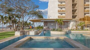 Relax by the resort's large pool surrounded by palm trees and a grassy lawn.