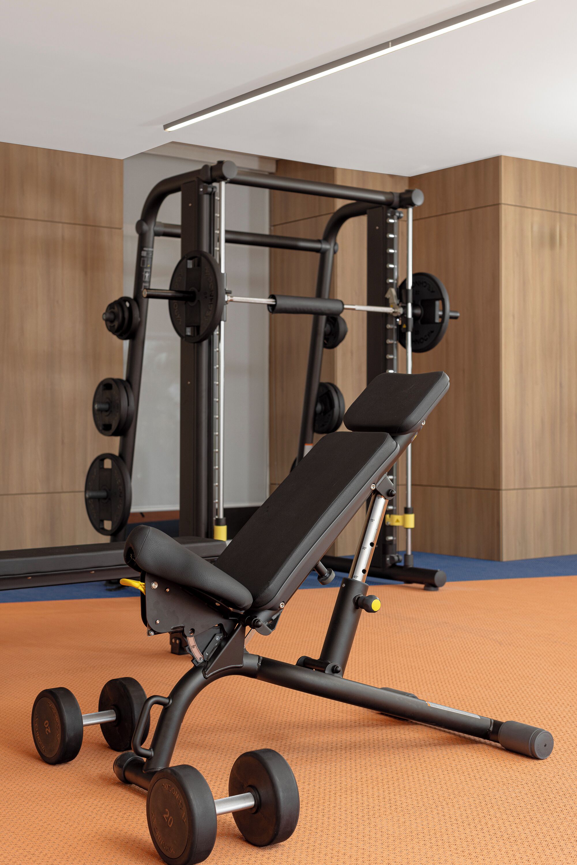 Une salle de sport équipée d’un banc de développé couché, de poids et d’un support à squats.