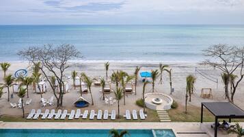 Un resort frente a la playa con piscina, sillones de descanso y una silla colgante.
