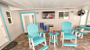 Une pièce avec des chaises et des tables turquoise, un téléviseur et un panneau indiquant les heures de silence.