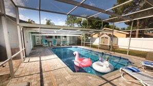Une piscine intérieure dotée d’un toit en verre, de chaises longues et de bouées en forme de cygne gonflable.