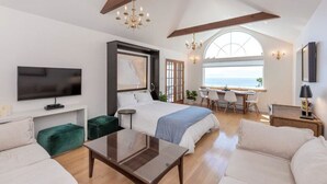 Un dormitorio amplio con una cama grande, un escritorio y vista al mar.