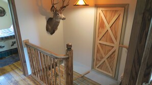 A staircase with a wooden railing, a deer head mounted on the wall, and a wooden barn door. - Rural Getaway at Homestead Lodge (Bottineau)