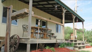 A rustic wooden building with a porch, a large wheel, and outdoor seating. - Rural Getaway at Homestead Lodge (Bottineau)