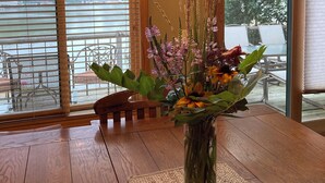 A wooden dining table with a vase of flowers and a candle holder. - Rural Getaway at Homestead Lodge (Bottineau)