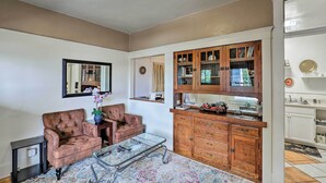 A living room with a brown leather armchair, a glass coffee table, and a wooden cabinet with glass doors. - 'St Patrick' Apartment in the Heart of Bisbee (Bisbee)