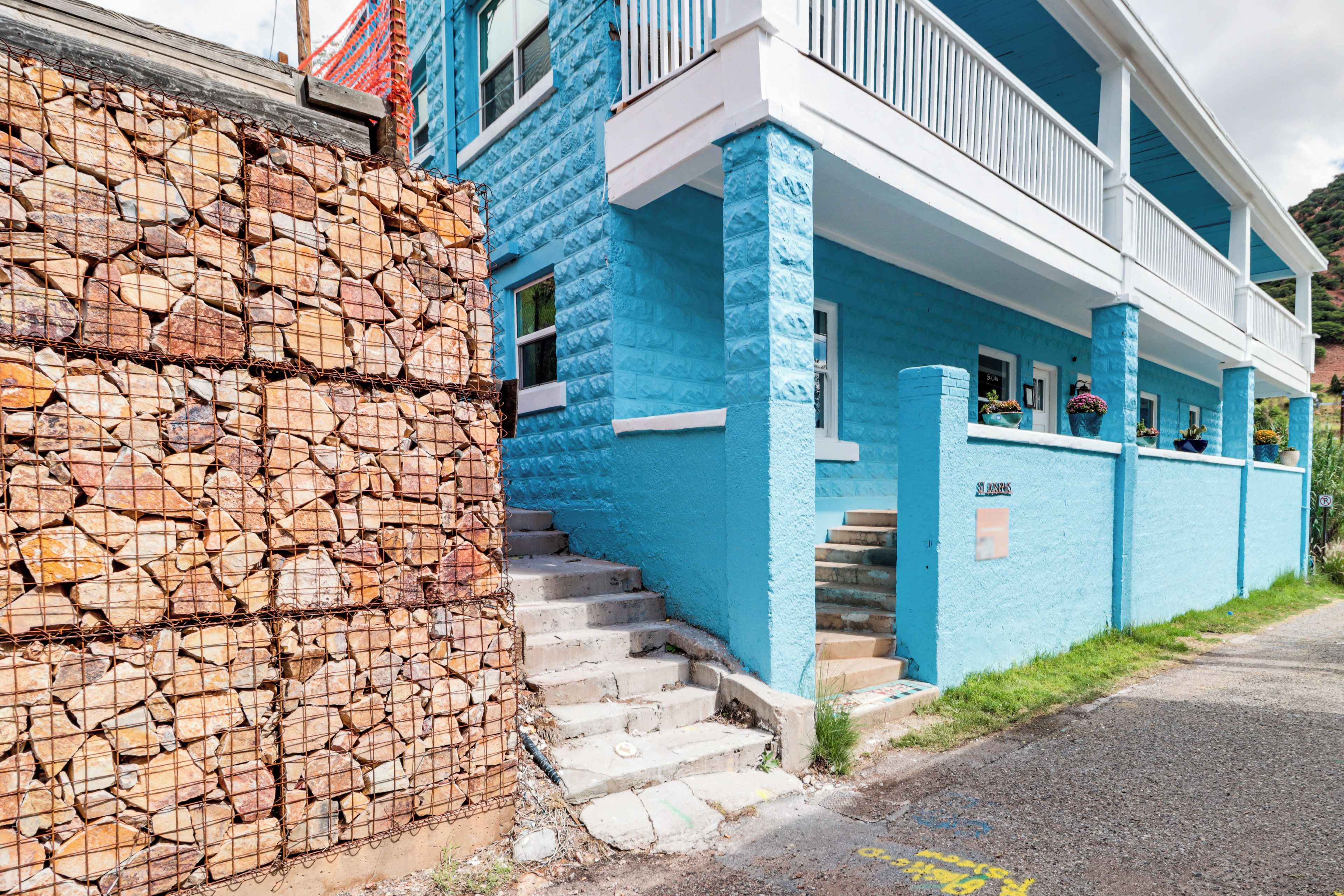 A two-story building with a stone wall on the left and a blue facade.
