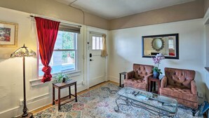 A living room with two leather sofas, a glass coffee table, a floor lamp, a patterned rug, and a door with a red curtain. - 'St Patrick' Apartment in the Heart of Bisbee (Bisbee)
