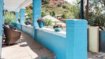 A covered outdoor seating area with wicker furniture and potted plants.