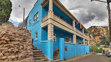 Un edificio de dos pisos con fachada azul, un balcón y una bandera.