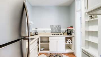 A compact kitchen with a refrigerator, a gas stove, and a sink. There are cabinets and a countertop with various kitchen items.