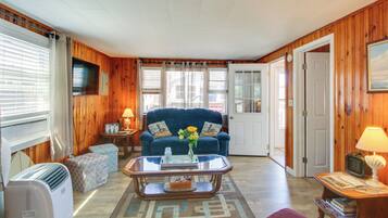 A living room with a blue sofa, a glass coffee table, and a television.