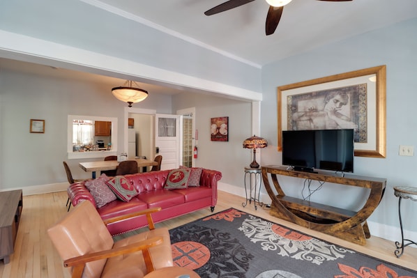 A living room with a red leather sofa, a wooden coffee table, a television, and a patterned rug. - 'St Valentine' Apartment w/ Balcony in Bisbee (Bisbee)