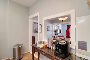 A kitchenette with a coffee maker, a trash can, and a table with various items. - 'St Valentine' Apartment w/ Balcony in Bisbee (Bisbee)