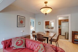 A modern living room with a red leather sofa, a dining table with chairs, a kitchen visible through an open door, and a ceiling light fixture. - 'St Valentine' Apartment w/ Balcony in Bisbee (Bisbee)
