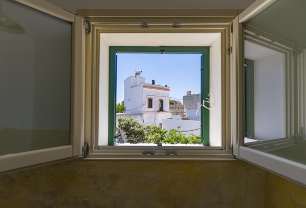 A room with a window opening to a view of buildings and a small tree. - Il Galletto bb (Patu)