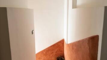 Una escalera con alfombra color beige que conduce a un rellano con dos macetas decorativas.
