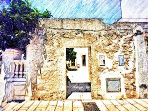 A stone building with a doorway, a small window, and a potted plant. - Il Galletto bb (Patu)