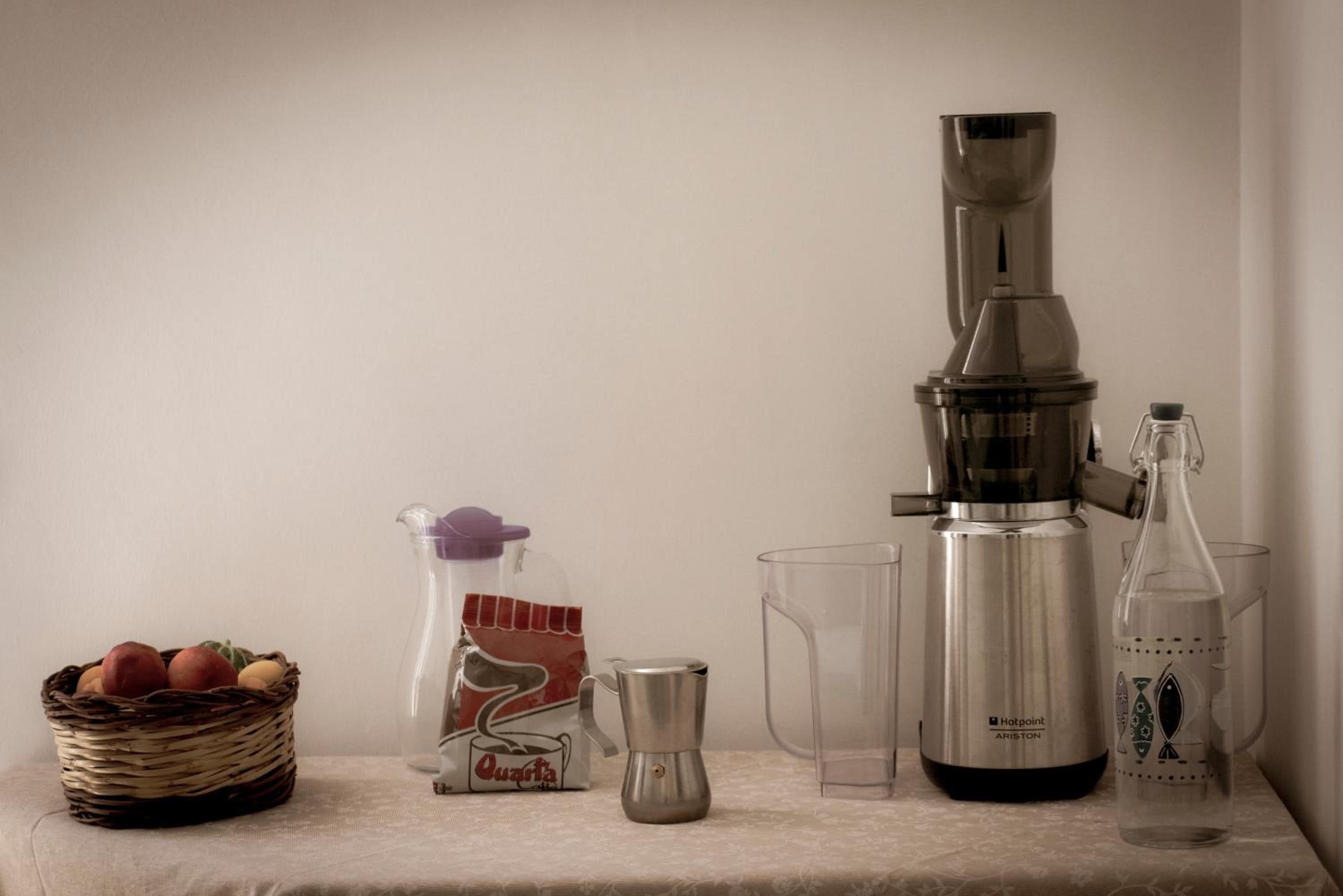 Een keukentrap met een koffiezetapparaat, een sapcentrifuge, een karaf, een glas en een mand met fruit.
