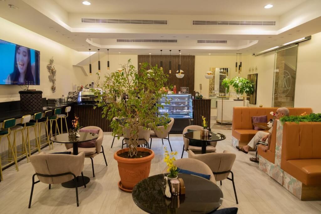 A modern hotel lobby with a bar area, seating arrangements, and a television screen.