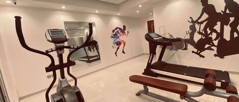 Un gimnasio moderno con cintas de correr, una bicicleta estática y una prensa de pesas.
