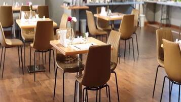A dining area with tables and chairs, some with flowers.