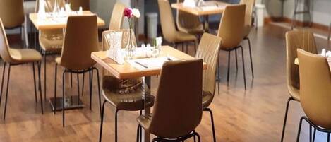 A dining area with tables and chairs, some with flowers.