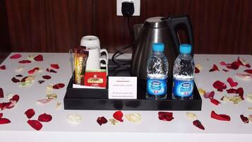 Ein Hotel-Rezeptionsbereich mit einer Kaffeemaschine, zwei Wasserflaschen, einer Snackbox und einem Schild.