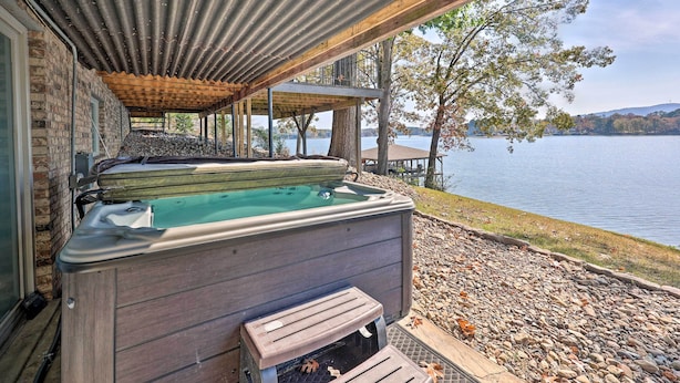 Un bain à remous sous une pergola en bois, avec vue sur un lac et des arbres.