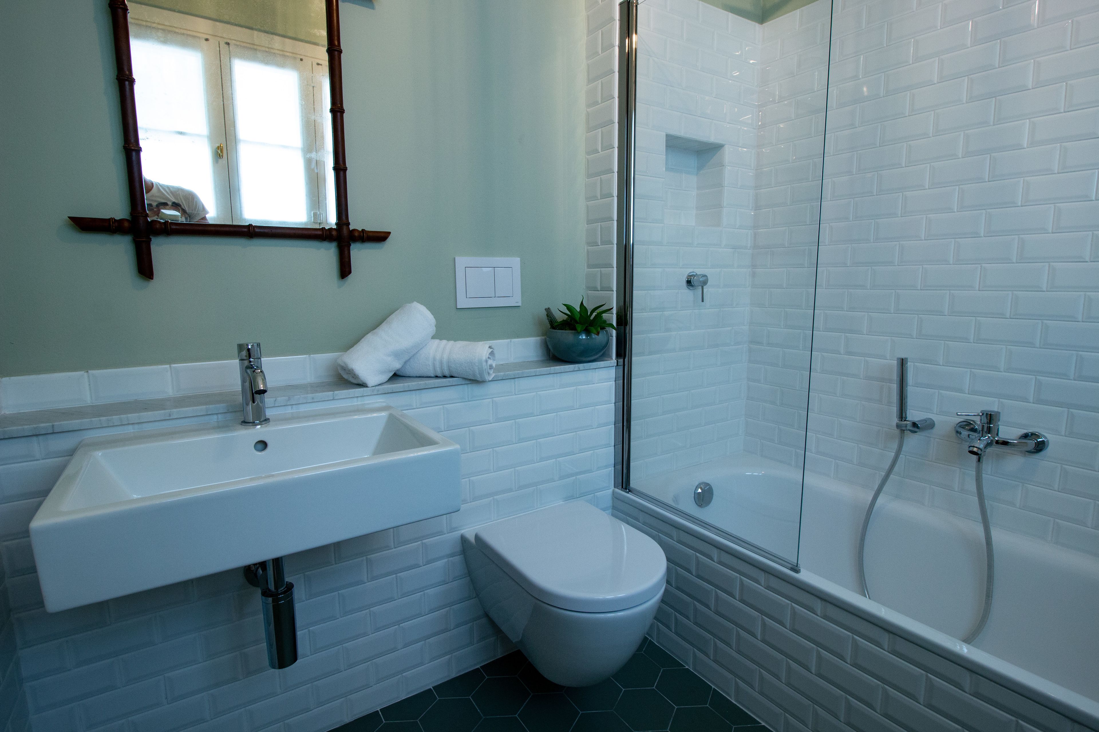 Un baño moderno con lavamanos blanco, inodoro y ducha con mampara de vidrio.