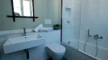 Un baño moderno con lavamanos blanco, inodoro y ducha con mampara de vidrio.