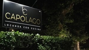 Letrero nocturno de un restaurante llamado "Capolago" con el lema "Locanda con Cucina".