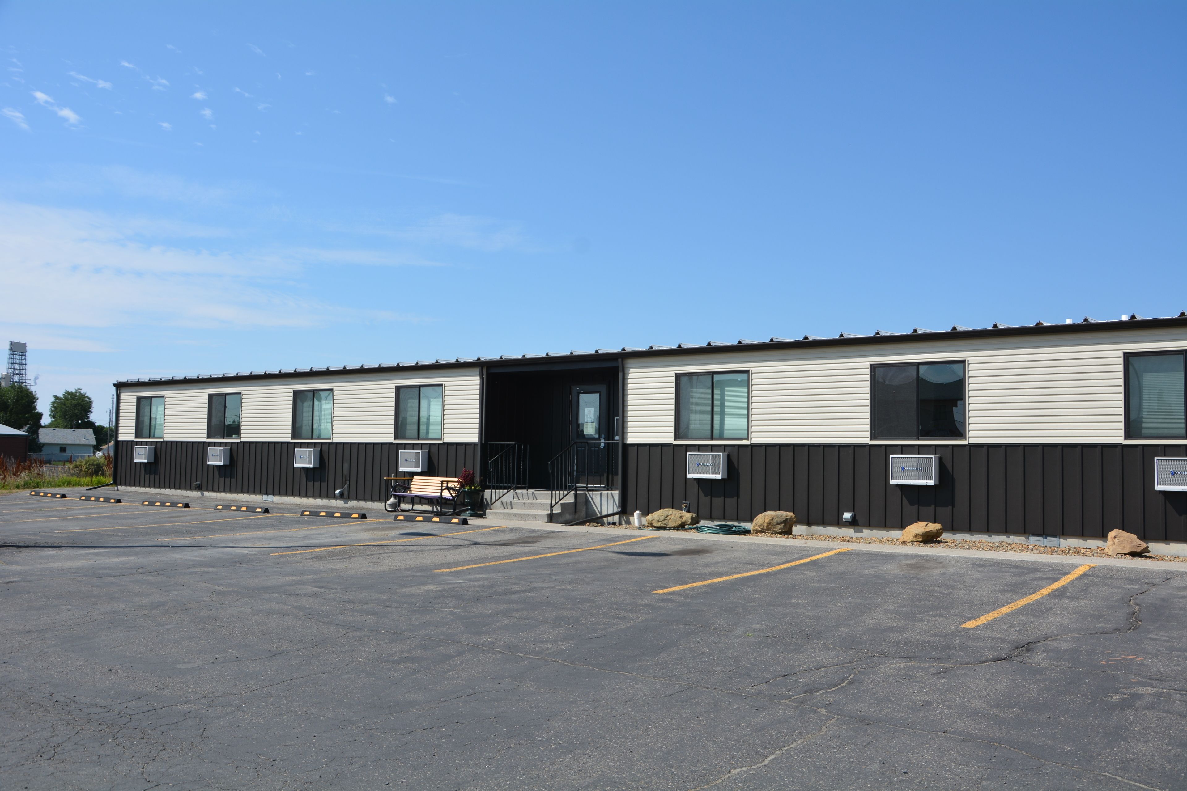 A building with a row of windows and a parking lot in front.