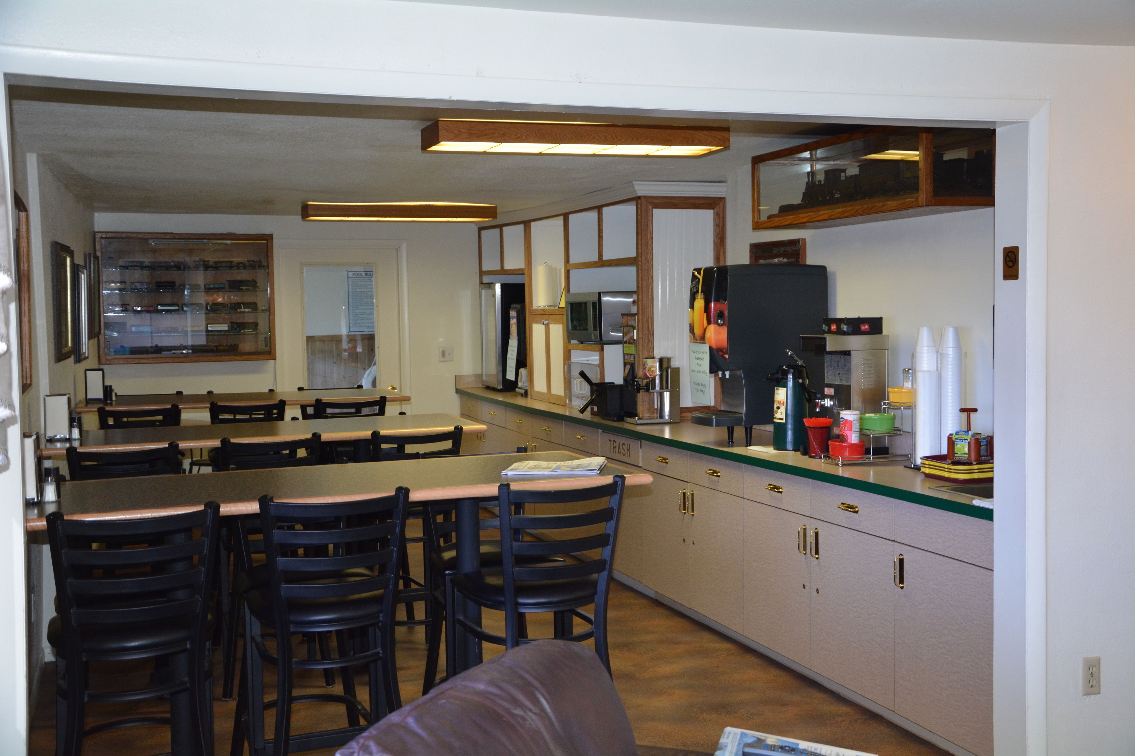 A kitchen with a dining area, equipped with a refrigerator, microwave, and coffee machine.