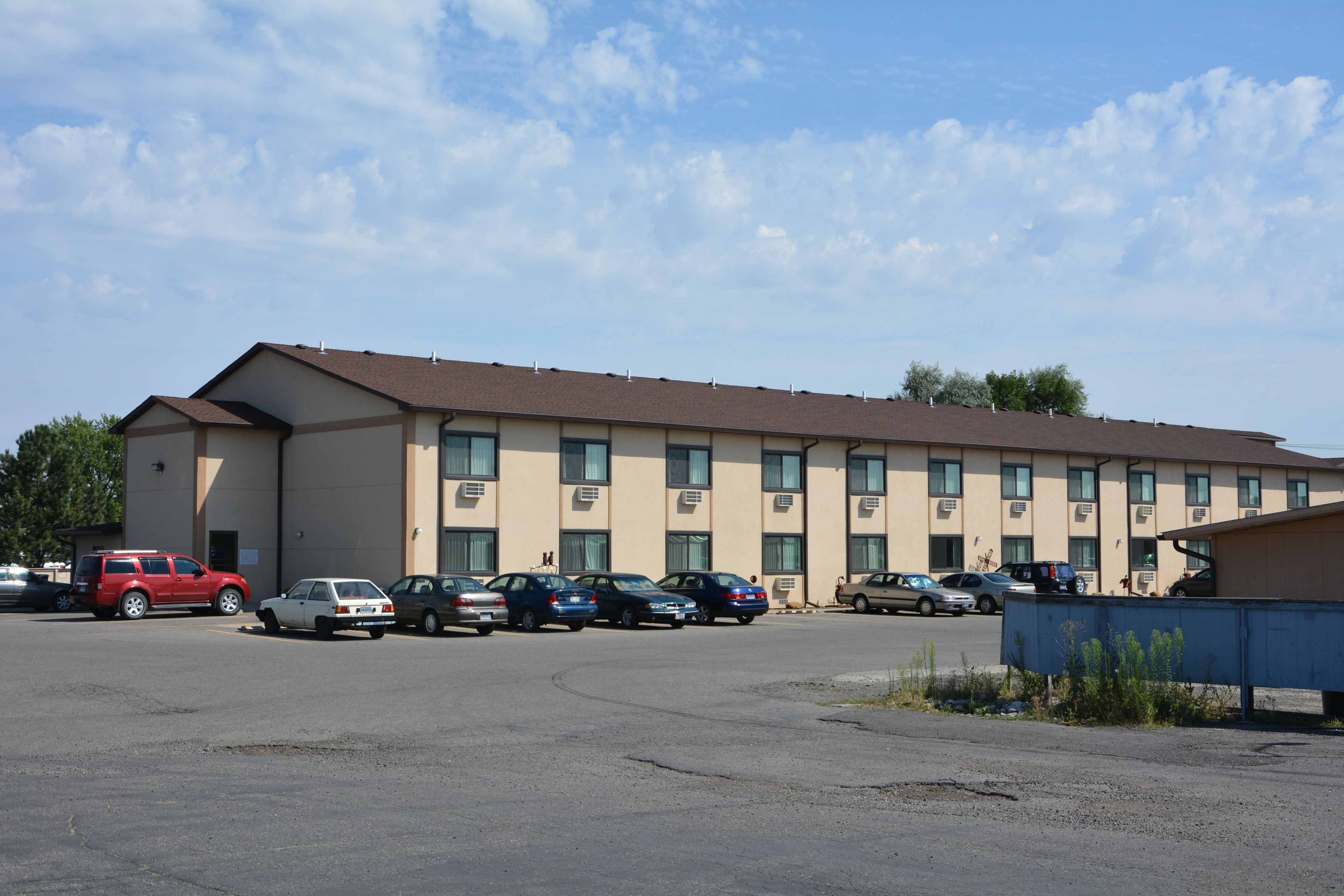 A motel with multiple rooms, a parking lot, and a building with a flat roof.