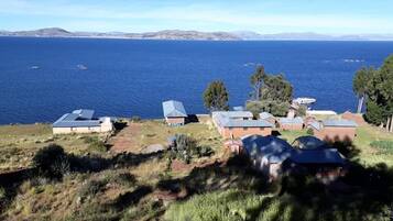 A coastal property with multiple buildings, some with sloped roofs, overlooking a large body of water with boats.